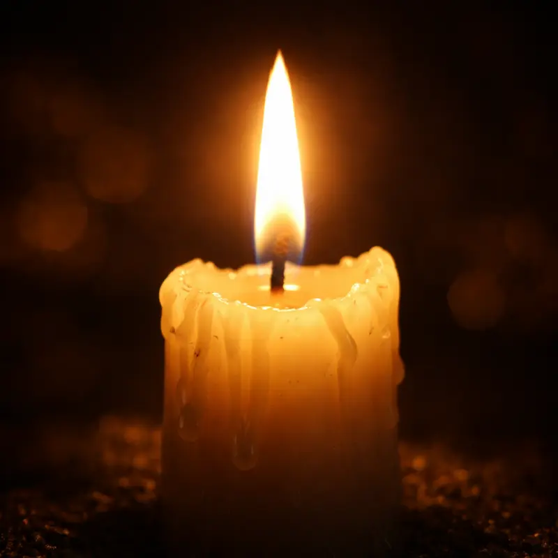 Vela casi consumida con llama firme en la oscuridad, imagen del noveno día de la novena